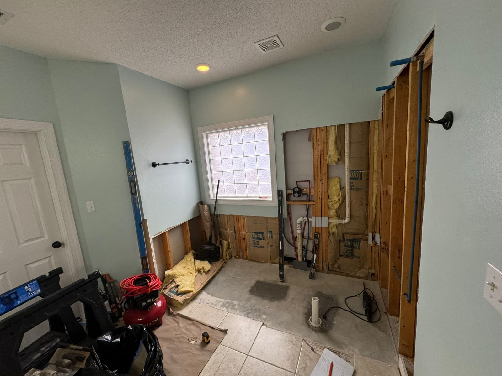 Bathroom renovation progress with plumbing and framing exposed